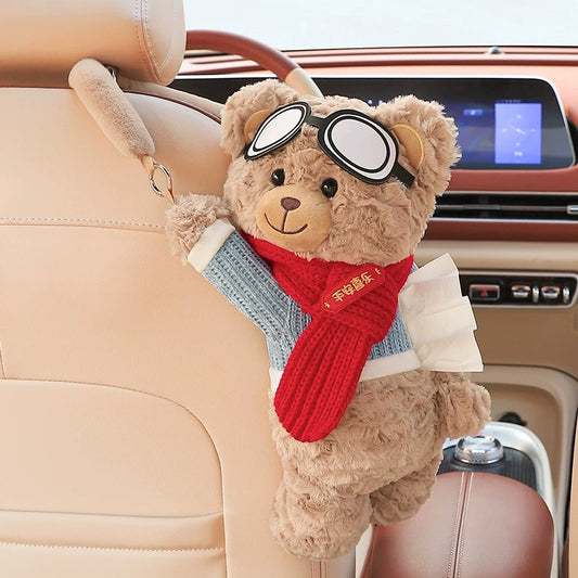 Teddy bear with goggles and a scarf hanging from a car's rearview mirror.