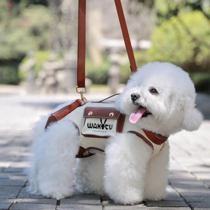 White fluffy dog wearing a brown and white bag with 'WANQIU' branding on a blurred outdoor background.