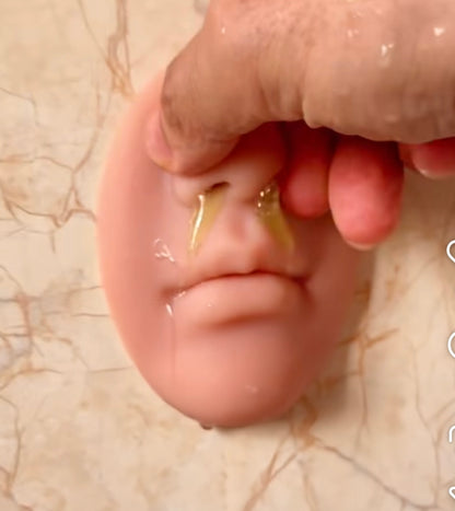 Close-up of a hand holding a silicone ear on a marble surface