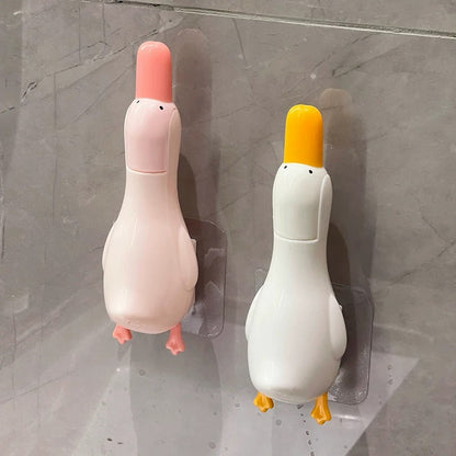 Two duck-shaped wall hooks on a gray tiled wall.