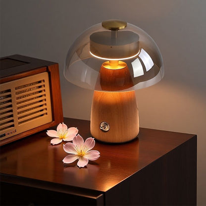 Wooden table lamp with glass shade on a wooden surface next to a vintage radio and flowers.