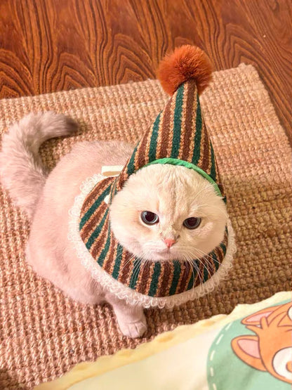 Cat wearing a striped hat with a pom-pom on a textured surface