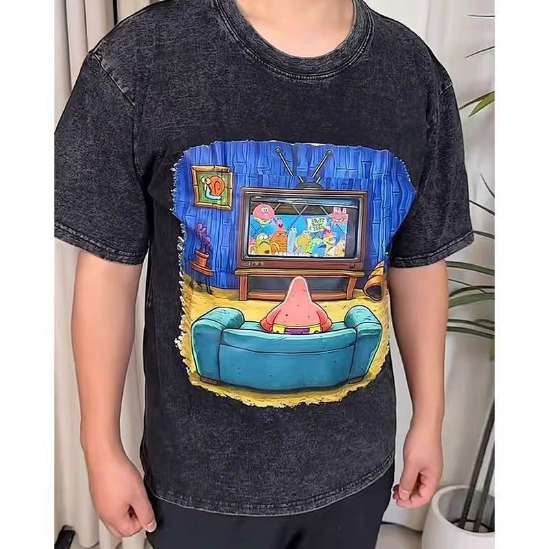 Person wearing a t-shirt with a colorful graphic of a character sitting on a couch watching TV.