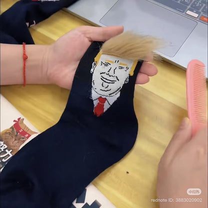 Navy blue sock with a printed face design held by a hand on a wooden surface.