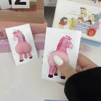 Pink unicorn tattoo on a white card held by a person with a blurred background