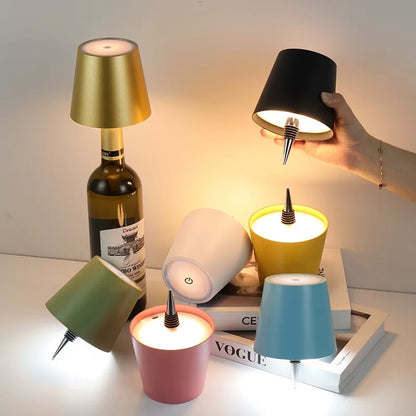 Colorful mini lamps being held and placed on a surface with books and a bottle.