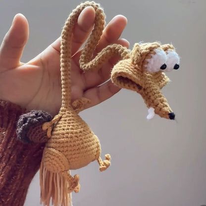 Hand holding a small crocheted dog toy with a plain background