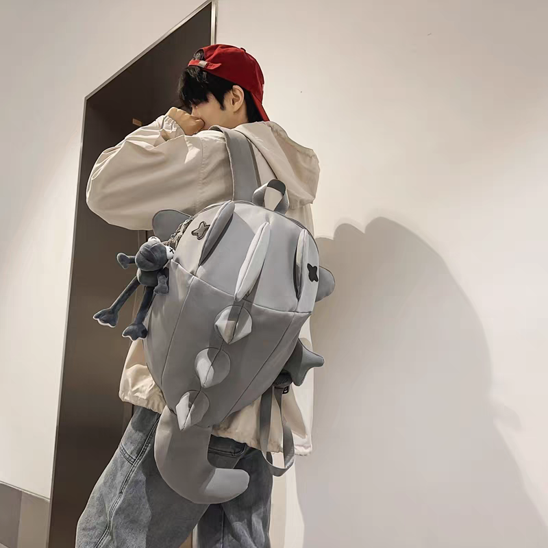 Person wearing a large gray backpack with a dragon design against a plain background