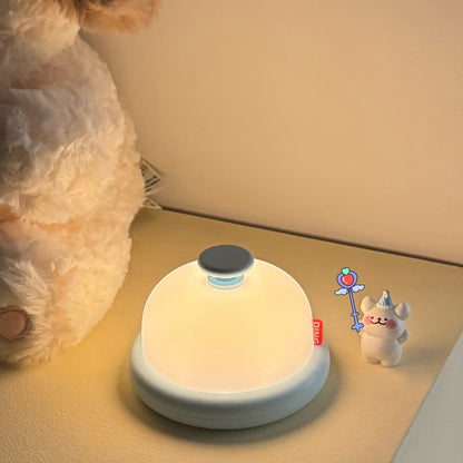 Round night light on a surface with a plush toy and small figurine in the background